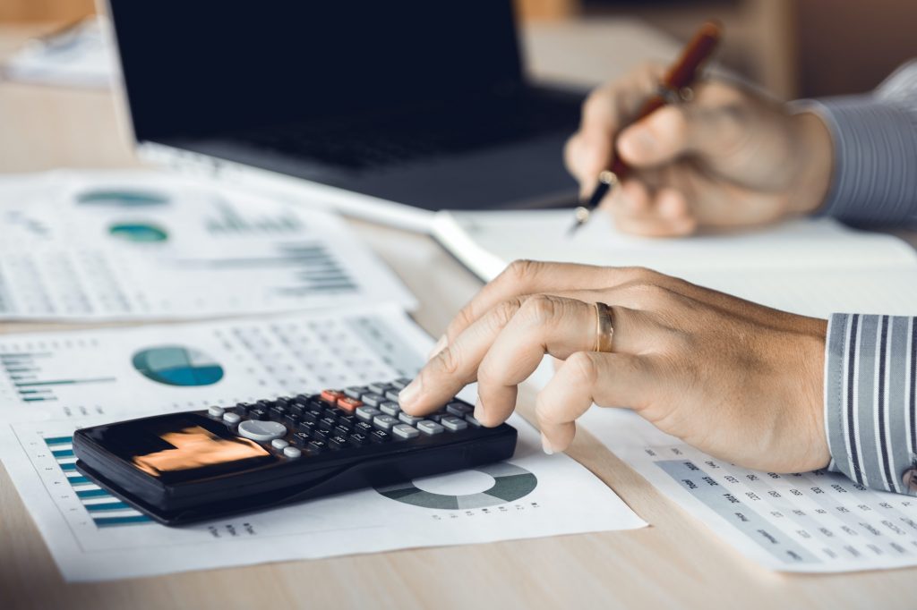 Businessman accountant pressing calculator and making calculation at table.