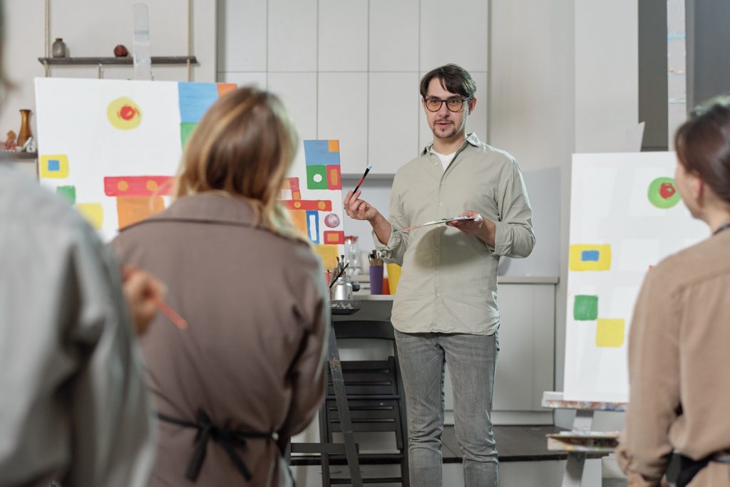 Confident teacher of painting explaining his students main rules of drawing